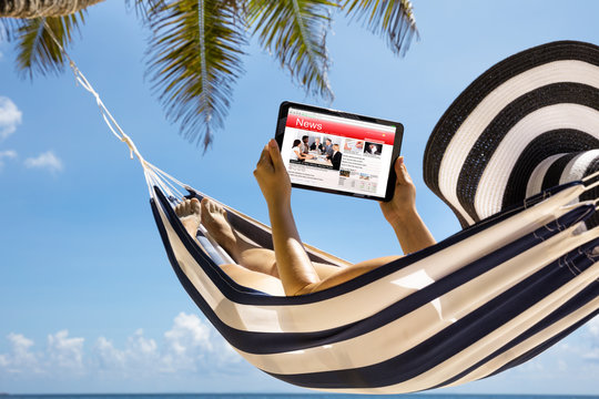 Woman Watching News On Digital Tablet Against Blue Sky