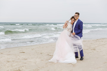 Fototapeta na wymiar newlyweds walking along the sea beach at the wedding. The groom hugs the bride
