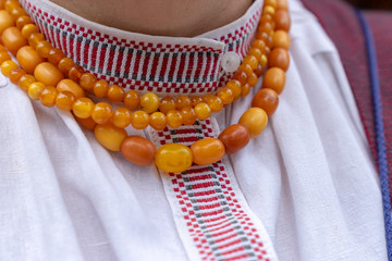 Fragment of a lithuanian woman's national costume. Amber necklace made of round details on the white linen woven shirt with pattern