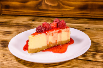 White plate with cheesecake New York and raspberries on wooden table