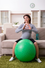Aged pregnant woman doing exercises at home 