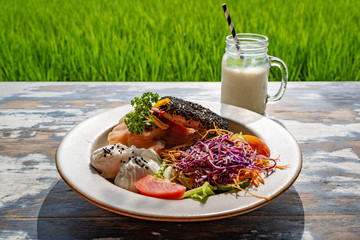 Healthy breakfast served on a vintage table with an emerald green rice field background. Concept of a healthy food and healthy lifestyle.