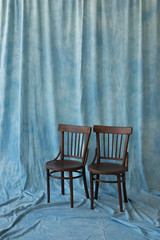 Fototapeta na wymiar two wooden brown chairs on a fabric blue background. vintage style