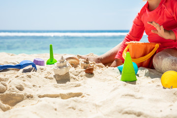 Toddler Girl Playing With Colorful Toys And Seashells On Sand
