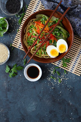 Noodles with vegetables and eggs in bowl on dark background. Top view with copy space. Asian food.