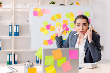 Young female employee in conflicting priorities concept 
