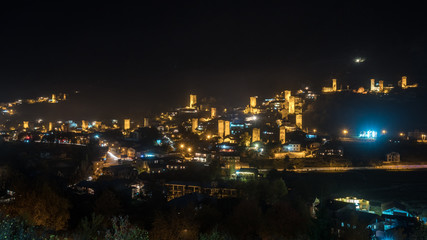 Fototapeta na wymiar View of Svan towers with night illumination in Mestia village at night. Svaneti, Georgia