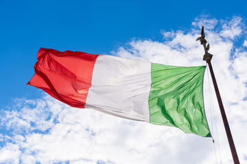 Flag of Italy in the wind. Sunny summer sky background