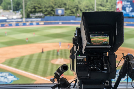 Broadcast television camera shooting a baseball game on a sunny day