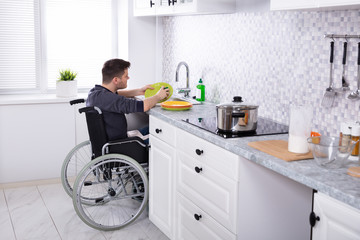 Handicapped Man Cleaning Dishes In Kitchen