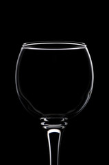 Wineglass consecrated by silhouette light with reflection on a black background