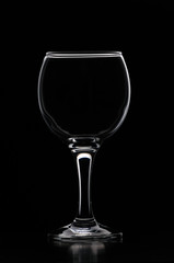 Wineglass consecrated by silhouette light with reflection on a black background