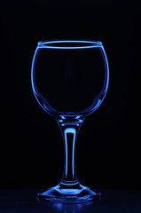Wineglass consecrated by silhouette light with reflection on a black background