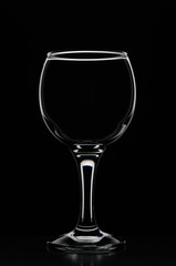 Wineglass consecrated by silhouette light with reflection on a black background
