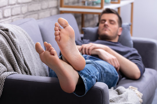 Man Relaxing On Sofa With His Legs
