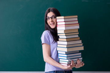 Young female teacher student in front of green board 