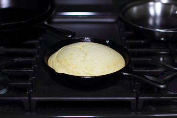 Cornbread in a cast iron skillet resting on the stove top.