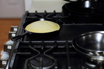 Cornbread in a cast iron skillet resting on the stove top.