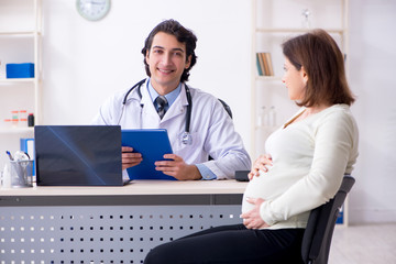 Old pregnant woman visiting young male doctor 