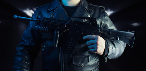 Biker in leather jacket holding rifle.
