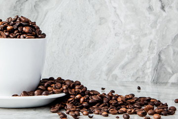 Black coffee in cup and coffee beans on marble background. Top view, space for text