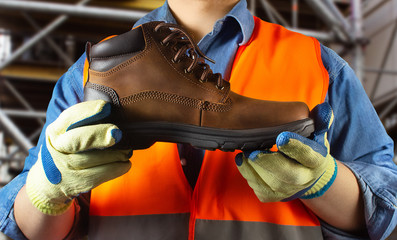 Worker in orange jacket outfit holding boot.