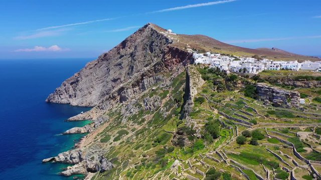 Aerial drone video of iconic and picturesque main village (chora) of Folegandros island featuring castle and built on top of steep hill overlooking the Aegean blue sea, Cyclades, Greece