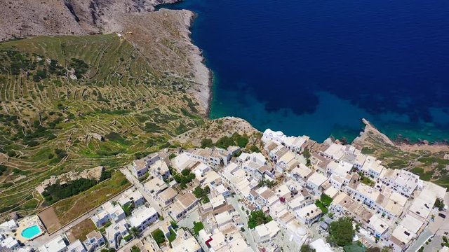 Aerial drone video of iconic and picturesque main village (chora) of Folegandros island featuring castle and built on top of steep hill overlooking the Aegean blue sea, Cyclades, Greece