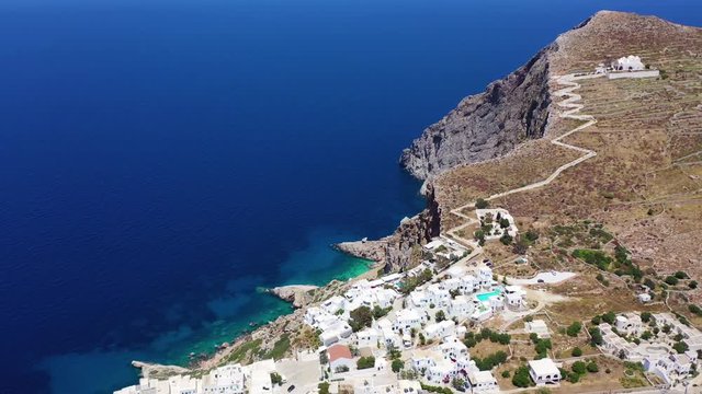 Aerial drone video of iconic and picturesque main village (chora) of Folegandros island featuring castle and built on top of steep hill overlooking the Aegean blue sea, Cyclades, Greece