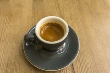 Porcelain cup with coffee on wooden bottom