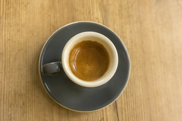 Porcelain cup with coffee on wooden bottom