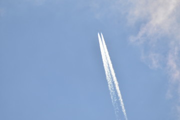 airplane with contrail in sunny sky at very high altitude