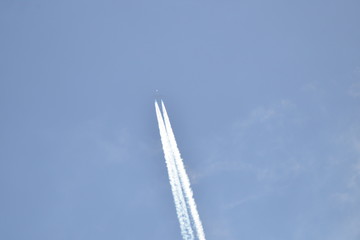airplane with contrail in sunny sky at very high altitude
