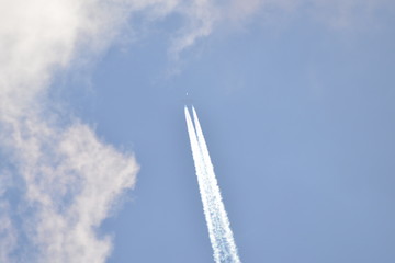 airplane with contrail in sunny sky at very high altitude
