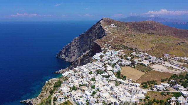 Aerial drone video of iconic and picturesque main village (chora) of Folegandros island featuring castle and built on top of steep hill overlooking the Aegean blue sea, Cyclades, Greece