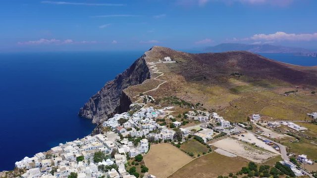 Aerial drone video of iconic and picturesque main village (chora) of Folegandros island featuring castle and built on top of steep hill overlooking the Aegean blue sea, Cyclades, Greece