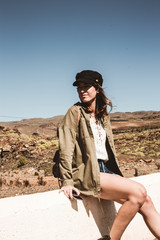 Fashion woman sitting on a white curb in a desert area