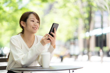 オープンカフェでスマートフォンを使う女性
