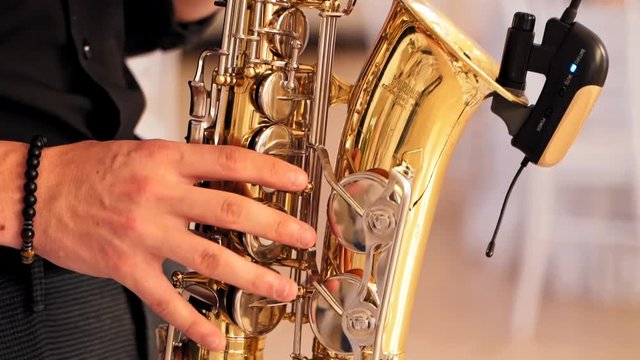 Male saxophonist playing on instrument. Close up view of man playing on saxophone