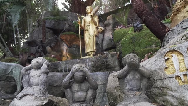 Slow, tilt up shot of three wise monkeys statue at golden mount temple Thailand, Bangkok. See no evil, hear no evil, speak no evil. Ornate water feature exterior religious shrine.