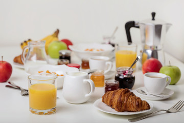Breakfast time. Croissants and orange juice, jam and honey. Coffee with cream or milk. Fruits - bananas, red and green apples. Ricotta with sour cream, nuts and dried apricots.