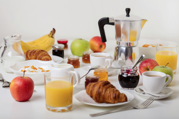 Breakfast time. Croissants and orange juice, jam and honey. Coffee with cream or milk. Fruits - bananas, red and green apples. Ricotta with sour cream, nuts and dried apricots.