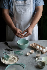 Making pancakes with chef. Chef at his workplace with cooking inventory and ingridients on a dark background.
