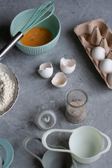 Pancake making process. Chef's workplace with cooking inventory and ingridients on a gray background.