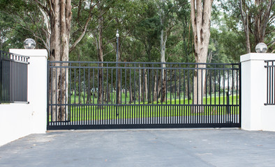 Metal driveway rural property entrance gates set in brick fence with lights and eucalyptus gum...