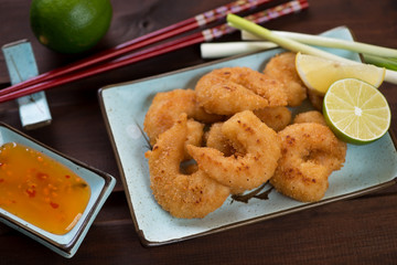 Fried king shrimps in panko breading on a turquoise plate, studio shot on a brown wooden background
