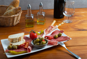 Antipasto on a white dish with bread and olive oil