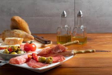 Antipasto on a white dish with bread and olive oil