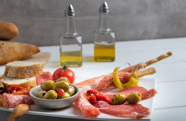 Antipasto on a white dish with bread and olive oil