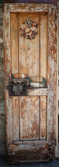 Tuscany an old painted wooden door with rusty lock and handles. On the door is painted blocks of cheese and clams